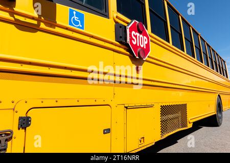 Ein großes rotes Stoppschild neben einem gelben Schulbus. Stockfoto