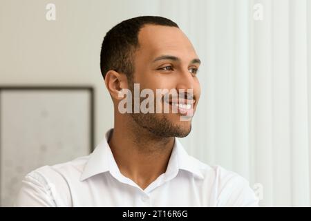 Porträt eines hübschen jungen Mannes in weißem Hemd drinnen Stockfoto