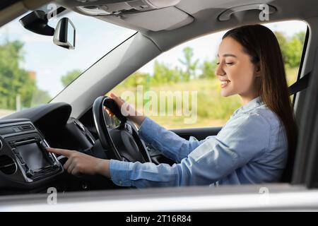 Auswählen des bevorzugten Funkgeräts. Schöne junge Frau, die im Auto den Knopf auf das Audio drückt Stockfoto