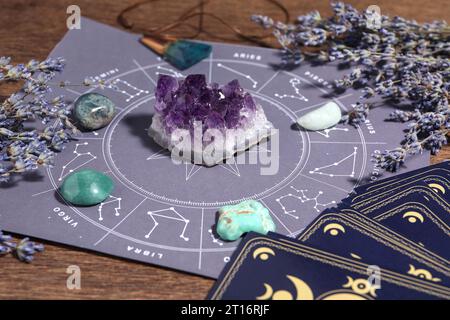 Astrologie-Vorhersage. Zodiac-Rad, Edelsteine, Tarotkarten und Lavendel auf Holztisch, Nahaufnahme Stockfoto