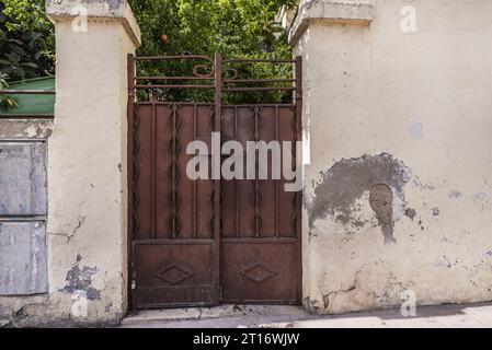 Beschädigtes Metallportal an der Wand eines Einfamilienhauses Stockfoto