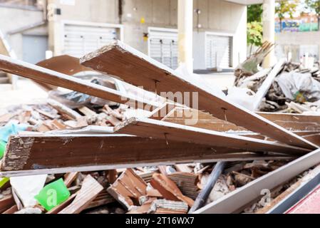 Holz- und Ziegelabfälle aus einer Hausrenovierung werden in einem Container auf der Straße deponiert Stockfoto