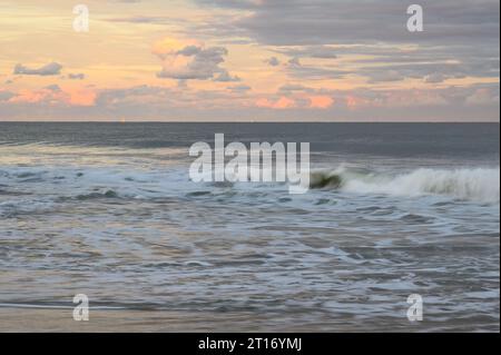 Wellen stürzen am Strand von Ocean City, Maryland, ab, während die untergehende Sonne den Himmel erleuchtet Stockfoto