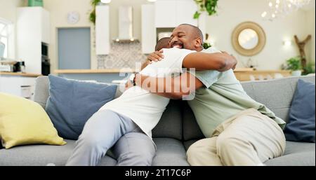 Umarmen, reden und Vater und Sohn auf dem Sofa für einen Besuch, Freundschaft oder Dankbarkeit. Happy, House und ein afrikanischer Vater, der einen erwachsenen Mann zur Begrüßung umschließt Stockfoto