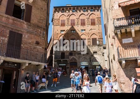 Siena, Italien-10. august 2020: Menschen und Touristen schlendern an einem sonnigen Tag durch die engen Gassen von Siena Stockfoto