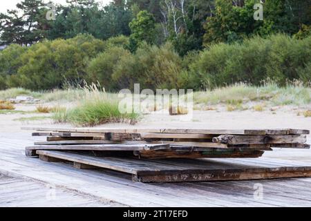Ein Stapel Holzplanken am Meeresrand vor einem Hintergrund aus Greenwood Stockfoto