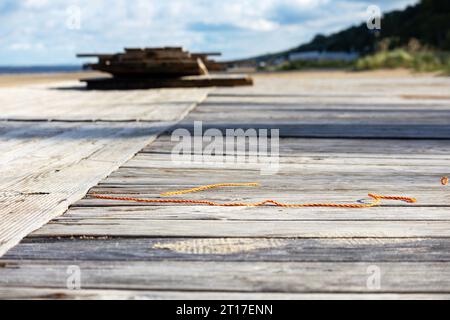 Ein Stapel Holzplanken am Meeresrand vor einem Hintergrund aus Greenwood Stockfoto