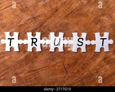 Draufsicht weißes Puzzle mit dem Wort TRUST auf Holzhintergrund. Stockfoto