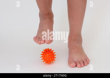 Abgeschnittene Kinderbeine beim Üben mit stacheliger Nadelkugel Stockfoto