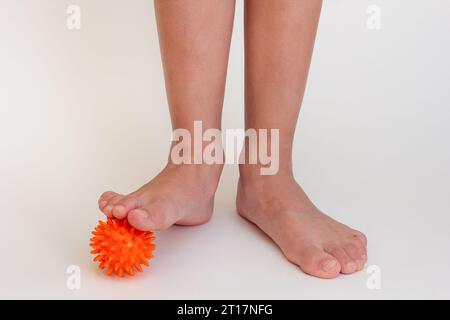 Abgeschnittene Kinderbeine beim Üben mit stacheliger Nadelkugel Stockfoto