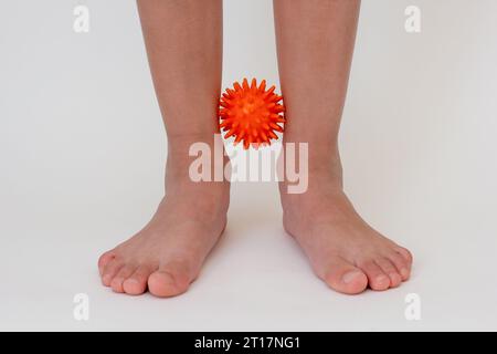 Abgeschnittene Kinderbeine beim Üben mit stacheliger Nadelkugel Stockfoto