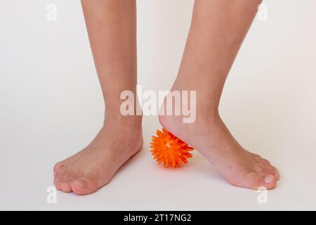 Abgeschnittene Kinderbeine beim Üben mit stacheliger Nadelkugel Stockfoto