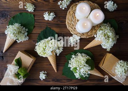 Hortensie-Blüten werden in Eiskegeln gesammelt und liegen mit Geschenken auf dem Tisch. Hochwertige Fotos Stockfoto