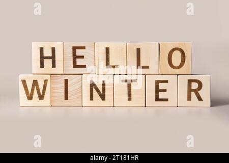 The Word Hello Winter auf Holzwürfeln auf beigefarbenem neutralen Studiohintergrund. Kopierbereich. Geschrieben. Textwörter sind wichtig. Weihnachtsdekoration. Beschriftung Stockfoto