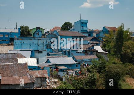 Tauchen Sie ein in den ruhigen Charme von Jodipan, Malang. Blaue Häuser bilden ein malerisches Viertel, das mit leuchtenden Farbtupfern geschmückt ist. Stockfoto