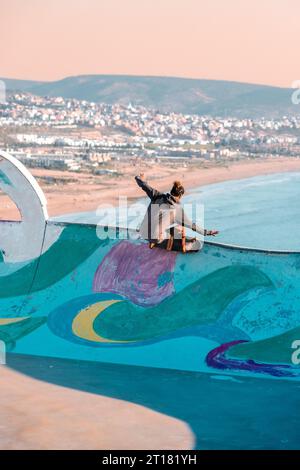 Ein aktiver junger Mann, der einen Skateboardtrick auf einer Rampe in Marokko macht Stockfoto