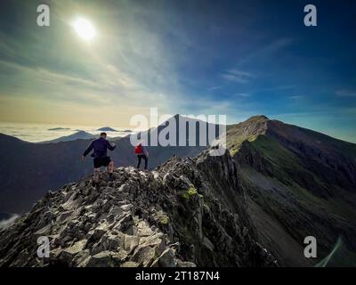 Klettermännchen auf der anspruchsvollen Crib Goch mit CRI-y-ddysgl und Snowdon in der Ferne an einem sonnigen Herbsttag. Wales. UK. Stockfoto