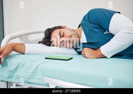 Schlafen, Krankenhaus und müde Arzt mit Telefon auf dem Bett für Ruhe, Nickerchen und Pause für Burnout, erschöpft und müde. Gesundheitswesen, Nachtschicht und Arbeiter Stockfoto