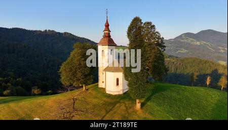 St. Thomas-Kirche in Skofja Loka, Slowenien, aus der Vogelperspektive bei Sonnenaufgang goldene Stunde Stockfoto