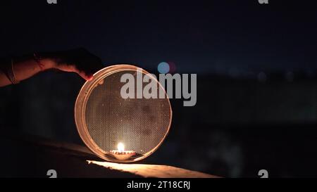 Karva Chauth ist ein eintägiges Festival, das von hinduistischen Frauen für die Sicherheit und Langlebigkeit ihrer Ehemänner gefeiert wird. Indianerin, die durch ein Sieb schaut, ce Stockfoto