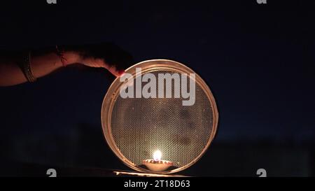 Karva Chauth ist ein eintägiges Festival, das von hinduistischen Frauen für die Sicherheit und Langlebigkeit ihrer Ehemänner gefeiert wird. Indianerin, die durch ein Sieb schaut, ce Stockfoto
