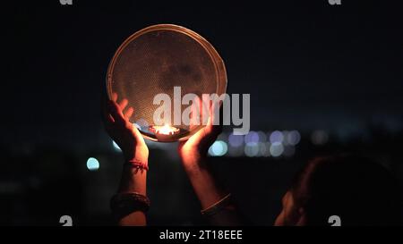 Karva Chauth ist ein eintägiges Festival, das von hinduistischen Frauen für die Sicherheit und Langlebigkeit ihrer Ehemänner gefeiert wird. Indianerin, die durch ein Sieb schaut, ce Stockfoto