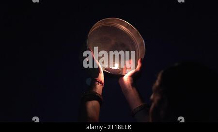Karva Chauth ist ein eintägiges Festival, das von hinduistischen Frauen für die Sicherheit und Langlebigkeit ihrer Ehemänner gefeiert wird. Indianerin, die durch ein Sieb schaut, ce Stockfoto