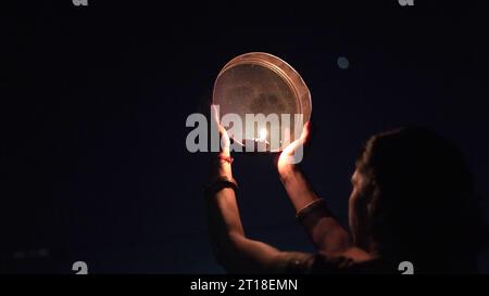 Karva Chauth ist ein eintägiges Festival, das von hinduistischen Frauen für die Sicherheit und Langlebigkeit ihrer Ehemänner gefeiert wird. Indianerin, die durch ein Sieb schaut, ce Stockfoto