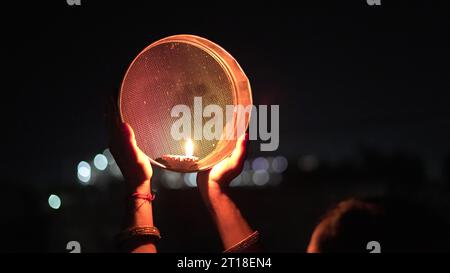 Karva Chauth ist ein eintägiges Festival, das von hinduistischen Frauen für die Sicherheit und Langlebigkeit ihrer Ehemänner gefeiert wird. Indianerin, die durch ein Sieb schaut, ce Stockfoto