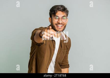Glücklicher junger indischer Mann, der laut lacht, nachdem er lächerliche Anekdoten gehört hat, Reaktion auf lustigen Witz, unbeschwert amüsiert. Positiver Lebensstil. Arabianer isoliert auf grauem Hintergrund Stockfoto