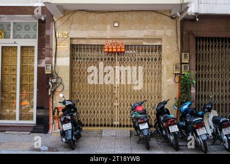 Der kleine Spiegel über der Tür verschreckt Dämonen aus dem Haus. Ho Chi Minh, Vietnam. Ein rot-goldenes Banner verkündet Glück und Glück. Stockfoto