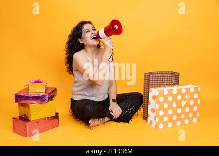 Indisches Mädchen mit Einkaufstasche und Ankündigung in Megaphone zum Verkauf und Angebote, Werbung für Einkaufskonzept Stockfoto