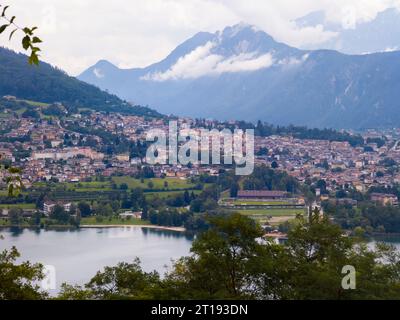 Aus der Vogelperspektive auf den Caldonazzo-See nördlich von Italien. Im Hintergrund die Bäume, die Alpen, der blaue Himmel. Die Reflexion der Berge im Wasser. Herbstsaison. Mehrfachkolben Stockfoto