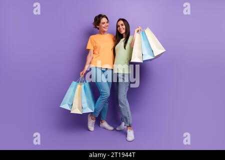 Volle Länge Beine Foto von zwei charmanten brünetten Haar Freundinnen haben Spaß freitag Verkauf zara Boutique isoliert auf violettem Hintergrund Stockfoto
