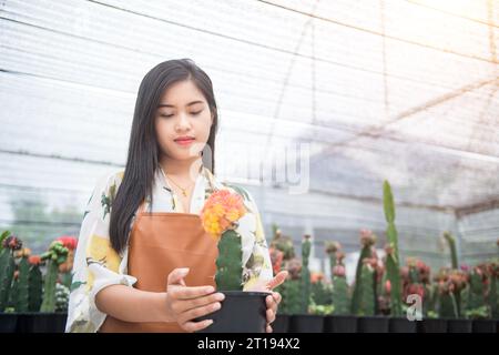 Porträt einer Frau, die Kakteen in einem Gewächshaus in Thailand pflegt Stockfoto