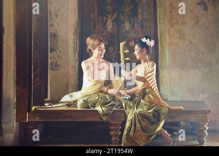 Zwei asiatische Frauen in traditioneller thailändischer Kleidung mit einem thailändischen Saiteninstrument, Thailand Stockfoto