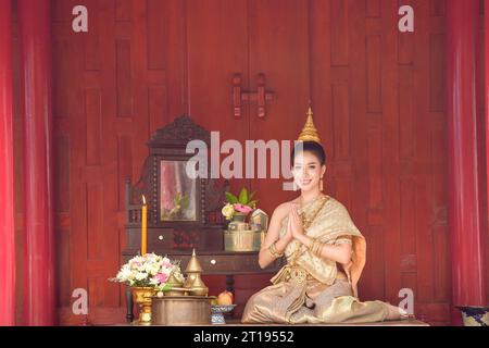 Lächelnde Thai-Frau, die mit den Händen in Gebetsposition sitzt, Thailand Stockfoto