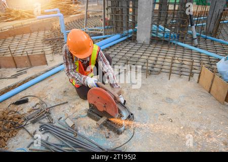 Bauarbeiter, der Stahl mit einem Schleifgerät auf einer Baustelle in Thailand schneidet Stockfoto