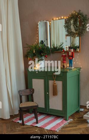 Spiegel über einem Sideboard in einem Wohnzimmer, dekoriert mit Lichterketten, Kranz, Weihnachtsdekorationen und Ornamenten Stockfoto