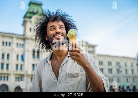Ein junger Mann isst Eis, während er seinen Urlaub in Triest genießt Stockfoto