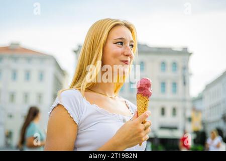 Ein Mädchen ist glücklich und lächelt, während es im Sommerurlaub Eis isst Stockfoto