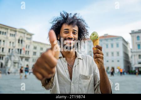 Ein Mann ist glücklich und zeigt beim Eisessen die Daumen hoch Stockfoto