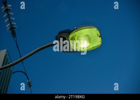 Nahaufnahme einer (grünen) Natriumdampflampe mit blauem Himmel im Hintergrund Stockfoto