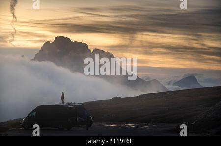 Unerkannte Person, die die dramatische Berglandschaft bei Sonnenuntergang genießt. Tre cime di lavadero in den italienischen Alpen Stockfoto