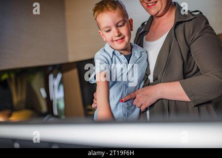 Der Vorschuljunge und seine Mutter in einem modernen naturhistorischen Museum, lesen Informationen auf einem Touchscreen-Display. Freizeitkonzept für Familien. Stockfoto