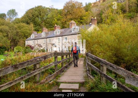 Backpacker spazieren über eine Fußgängerbrücke über den Fluss Wye bei Blackwell Mill in Monsal Dale am Anfang des Monsal Trail Derbyshire Peak District Stockfoto