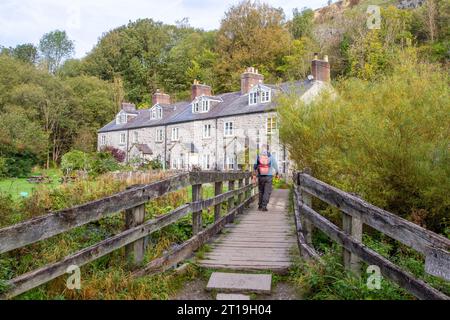 Backpacker spazieren über eine Fußgängerbrücke über den Fluss Wye bei Blackwell Mill in Monsal Dale am Anfang des Monsal Trail Derbyshire Peak District Stockfoto