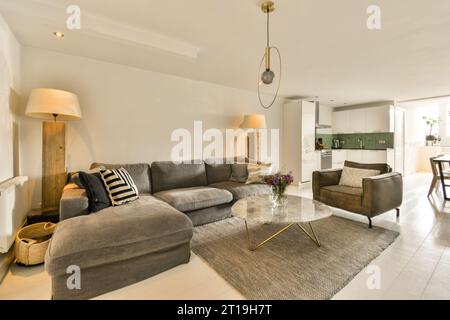 Ein Wohnzimmer mit zwei Sofas und einem Couchtisch auf dem Foto ist rechts aufgenommen, es gibt eine offene Küche Stockfoto