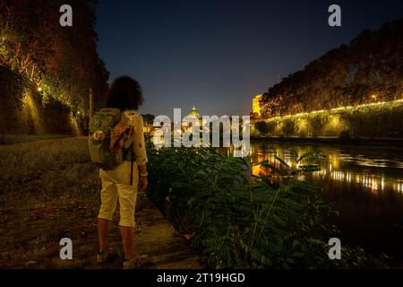 Die Frau steht nachts auf dem Tiber und schaut sich die Engelsburg an. Stockfoto