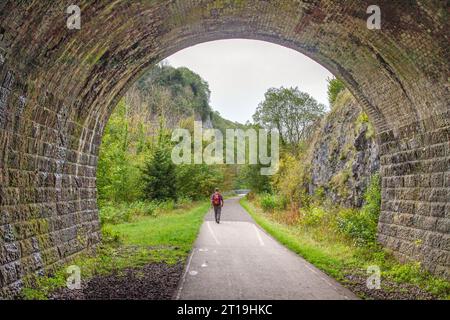 Man läuft auf dem Monsal Trail durch einen stillgelegten Eisenbahntunnel bei Chee Dale im Derbyshire English Peak District Stockfoto